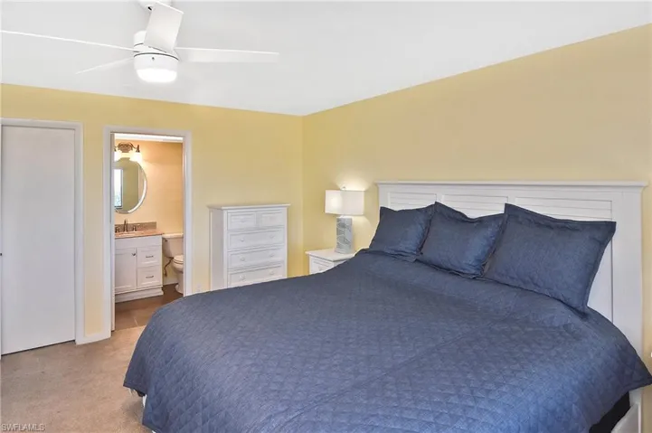 Bedroom featuring light carpet, ceiling fan, and connected bathroom