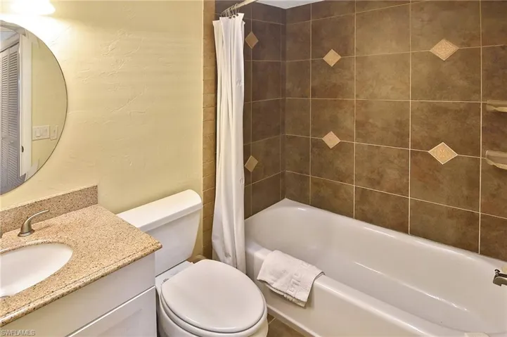 Full bathroom with vanity, a textured wall, and shower / tub combo with curtain