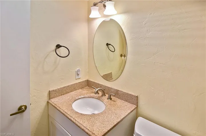 Half bathroom with a textured wall and vanity
