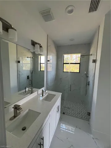 Bathroom with marble finish floor, a sink, and visible vents