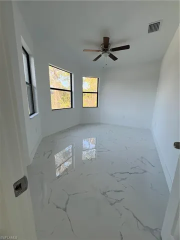 Spare room featuring a ceiling fan, marble finish floor, visible vents, and baseboards