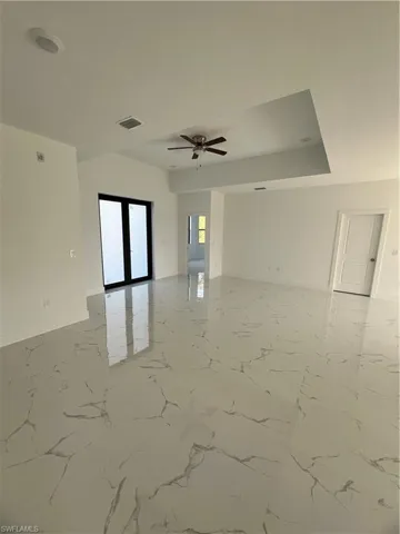 Empty room with baseboards, visible vents, a ceiling fan, marble finish floor, and french doors