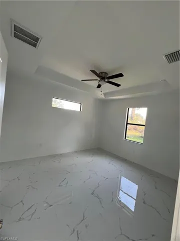 Unfurnished room with marble finish floor, a raised ceiling, and visible vents
