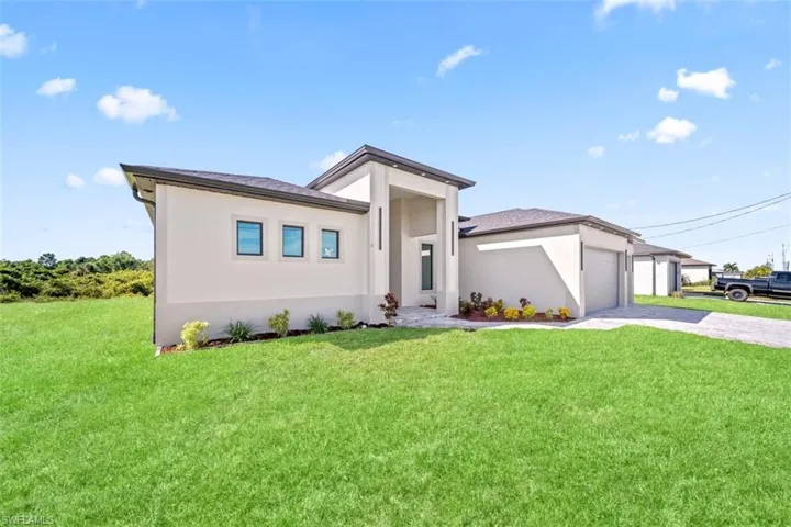 Contemporary stucco exterior with a multi-gabled roofline, three distinct window openings, a paver driveway, and an attached garage