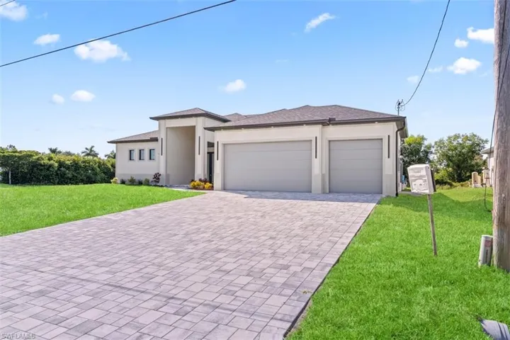 Contemporary exterior with a smooth stucco finish, dual garage doors, a paver driveway, and a covered entry