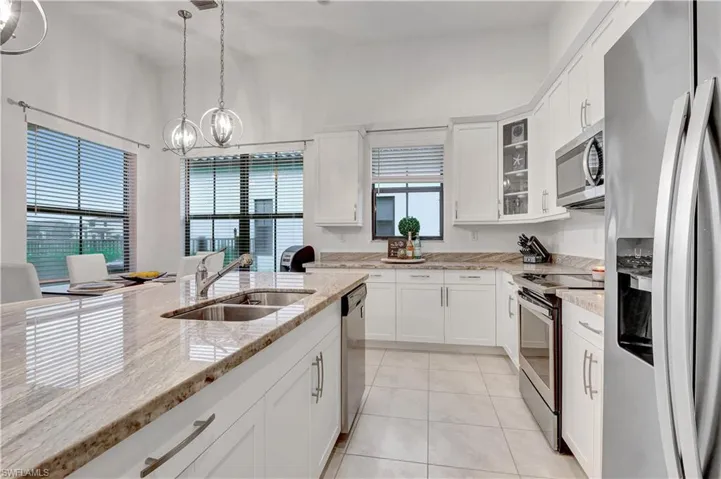 Kitchen featuring appliances with stainless steel finishes, sink, pendant lighting, and white cabinets