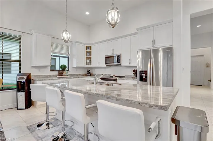 Kitchen with white cabinetry, appliances with stainless steel finishes, decorative light fixtures, and sink