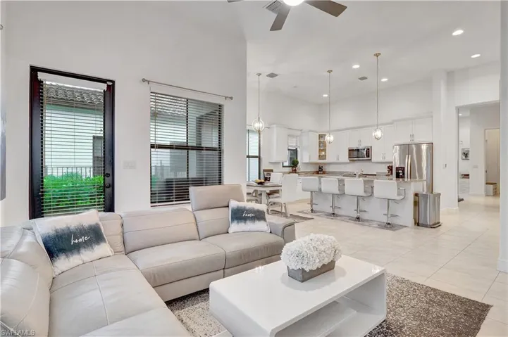 Living room with a towering ceiling, ceiling fan, and light tile patterned flooring