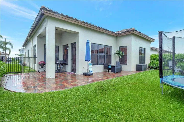 Back of property with a trampoline, a yard, and a patio area