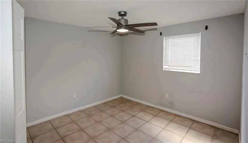 Neutral wall tones, tiled flooring, window with blinds, and a ceiling fan with integrated lighting