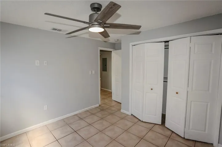 Neutral-toned tile flooring, light gray walls, and a modern ceiling fan with a light fixture