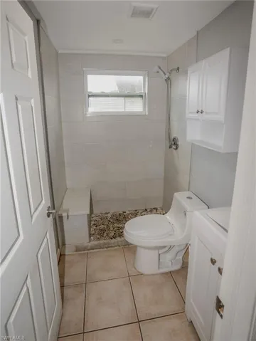Walk-in shower with pebble tile floor, subway tile walls, and a built-in bench