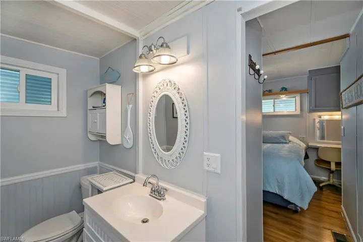 Bathroom featuring wood finished floors, vanity, wainscoting, and beam ceiling