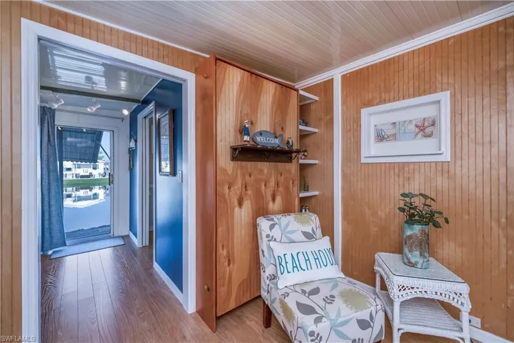 Living area featuring crown molding, wood walls, and wood finished floors