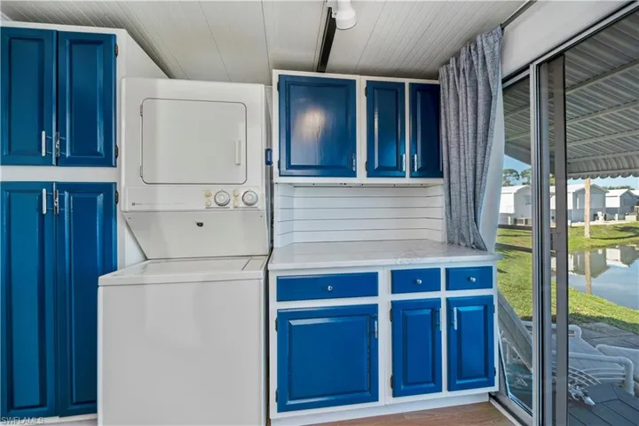 Washroom with estacked washer and dryer, cabinet space, wood ceiling, and wood finished floors