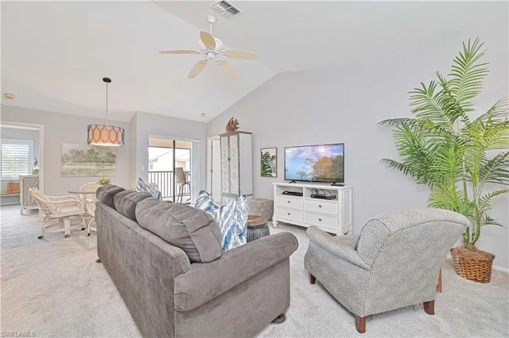 Living room with high vaulted ceiling, light carpet, a ceiling fan, and visible vents