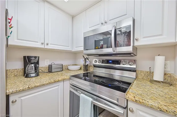 Kitchen featuring white cabinetry, light stone counters, and stainless steel appliances