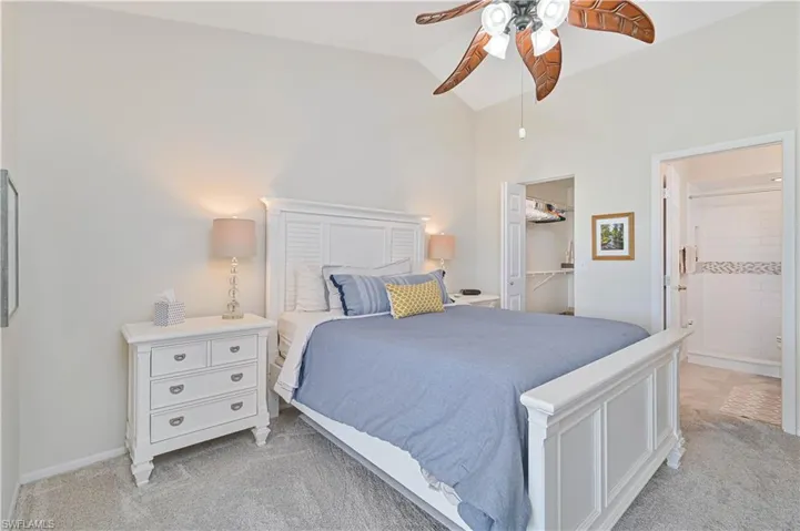 Bedroom with a ceiling fan, a closet, ensuite bathroom, a walk in closet, and light carpet
