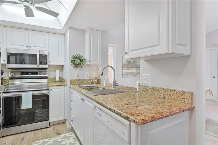 Kitchen with white cabinetry, stainless steel appliances, ceiling fan, and a sink