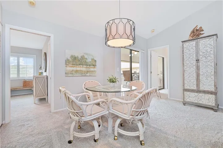 Carpeted dining room with vaulted ceiling and baseboards