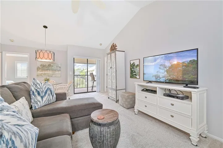Living room featuring light colored carpet, baseboards, a healthy amount of sunlight, and high vaulted ceiling