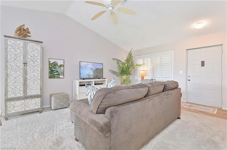 Carpeted living room featuring ceiling fan and lofted ceiling