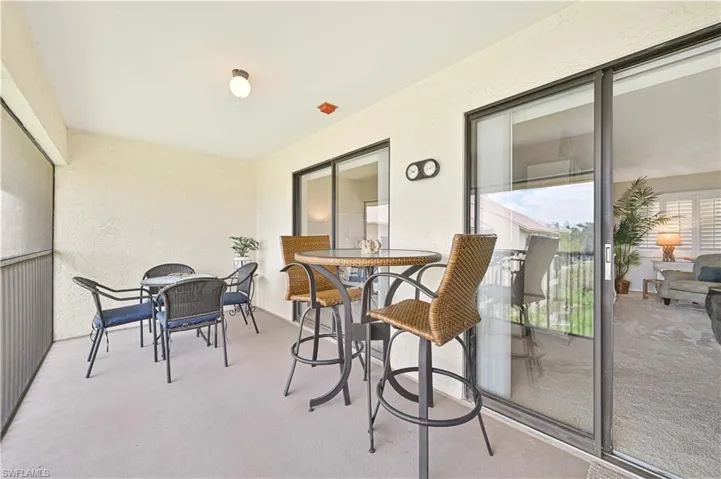Sunroom / solarium with a textured wall, carpet floors, and outdoor dining space