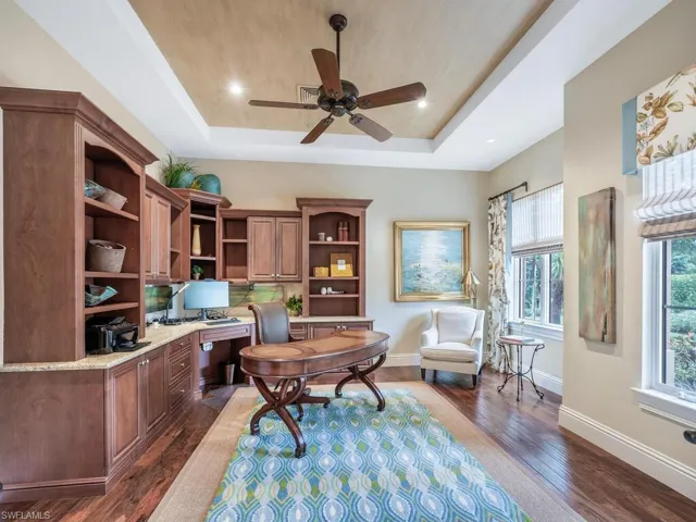 Office space with built-in cabinetry, wood flooring, a tray ceiling