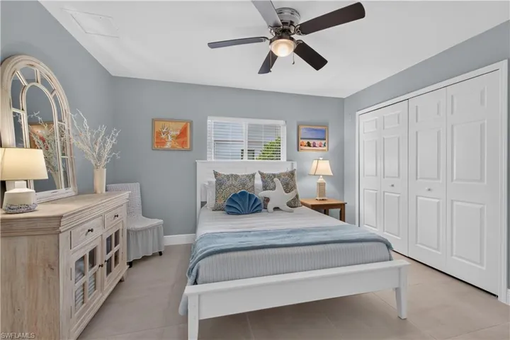 White bifold closet doors, light-toned tile flooring, and a ceiling fan with integrated lighting