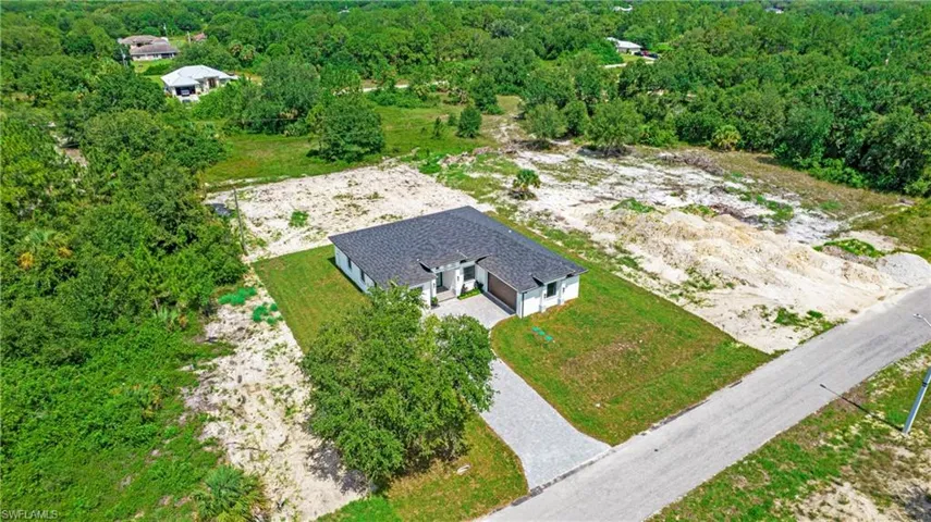 Aerial view of property and surrounding area with a forest