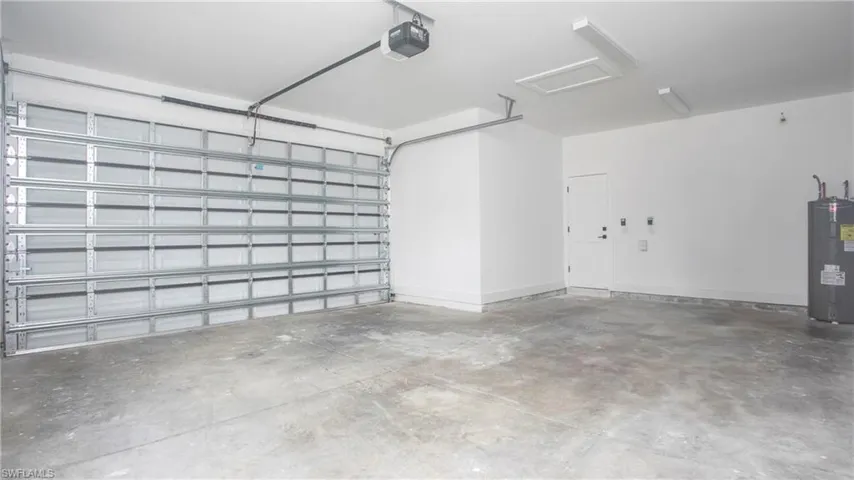 Garage featuring electric water heater and a garage door opener