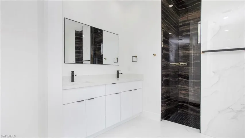 Full bathroom with double vanity, a marble finish shower, and marble finish flooring