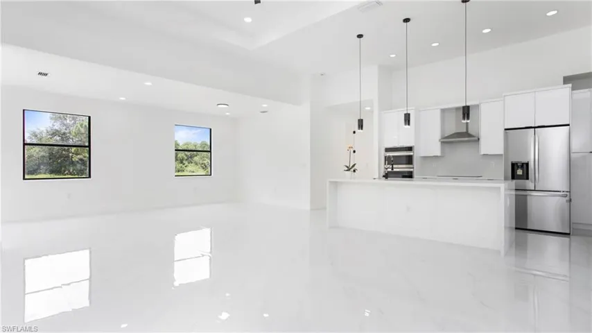 Kitchen with stainless steel appliances, modern cabinets, wall chimney range hood, white cabinetry, and recessed lighting
