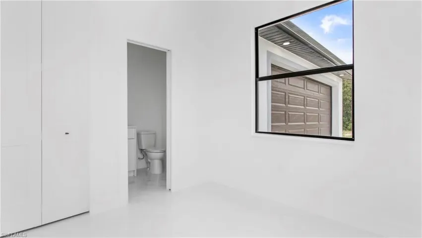 Unfurnished bedroom featuring ensuite bath and baseboards