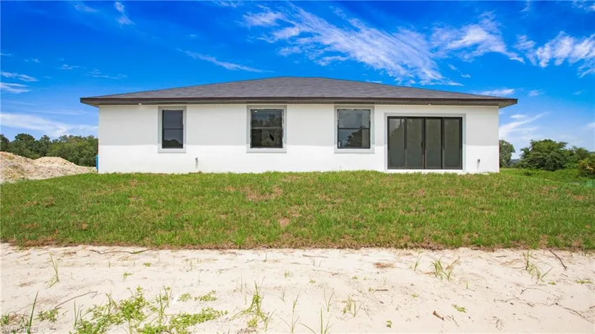 Back of property featuring stucco siding and a yard