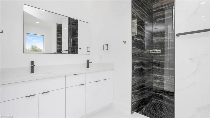 Full bathroom featuring double vanity and a marble finish shower