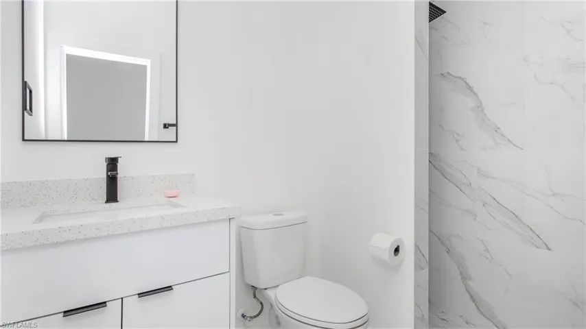 Bathroom with vanity and a marble finish shower