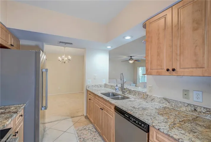 Kitchen with ceiling fan with notable chandelier, stainless steel appliances, hanging light fixtures, sink, and light tile floors
