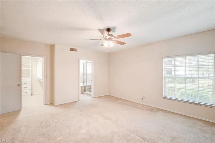 Carpeted spare room featuring plenty of natural light, ceiling fan, and a textured ceiling