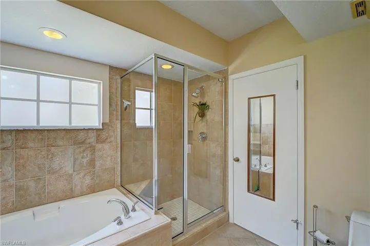 Bathroom featuring tile floors, a textured ceiling, toilet, and independent shower and bath