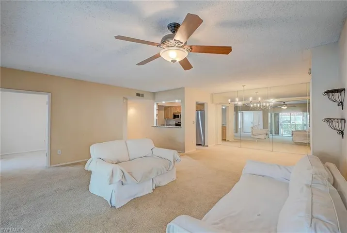 Living room with light carpet, a textured ceiling, and ceiling fan