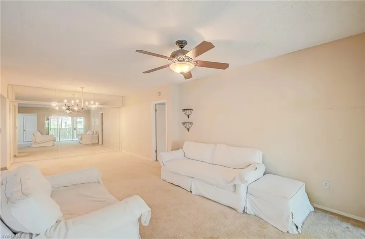 Carpeted living room featuring ceiling fan with notable chandelier