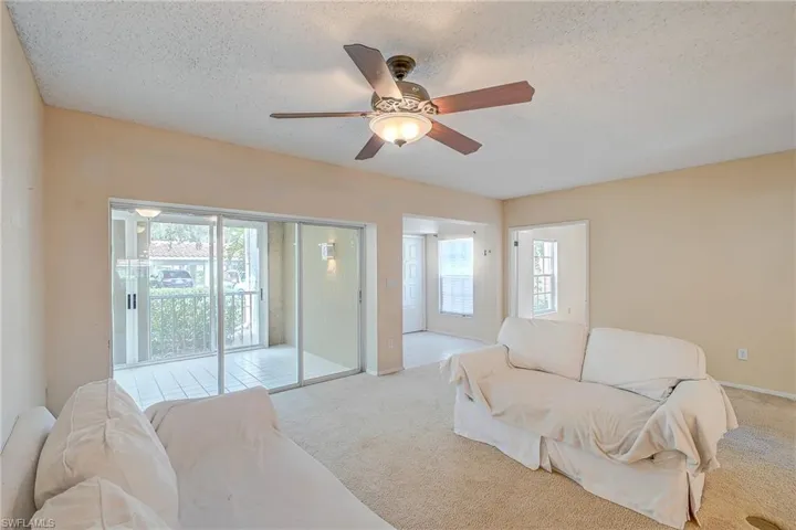 Carpeted living room featuring ceiling fan and a textured ceiling