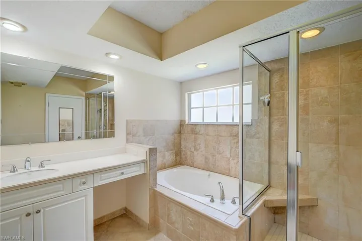 Bathroom with tile flooring, vanity, a textured ceiling, and shower with separate bathtub