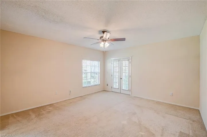 Spare room featuring ceiling fan, a textured ceiling, and light colored carpet