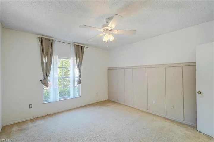 Carpeted empty room with a textured ceiling and ceiling fan