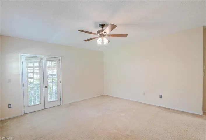 Carpeted empty room featuring french doors, ceiling fan, and a textured ceiling