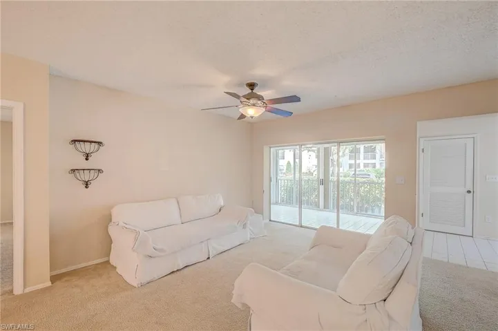 Tiled living room featuring ceiling fan and a textured ceiling