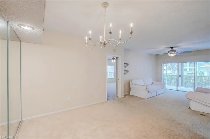 Unfurnished living room with carpet, ceiling fan with notable chandelier, and a textured ceiling