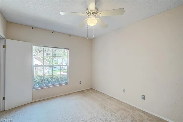 Carpeted spare room featuring a textured ceiling and ceiling fan